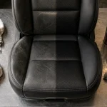 Entretien cuir voiture : siège en cuir noir partiellement nettoyé avant baume, microfibres